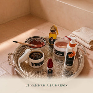 Coffret hammam marocain posé sur un sol en bejmat terracotta dans une salle de hammam
