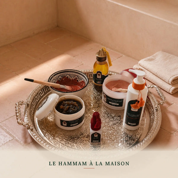 Coffret hammam marocain posé sur un sol en bejmat terracotta dans une salle de hammam