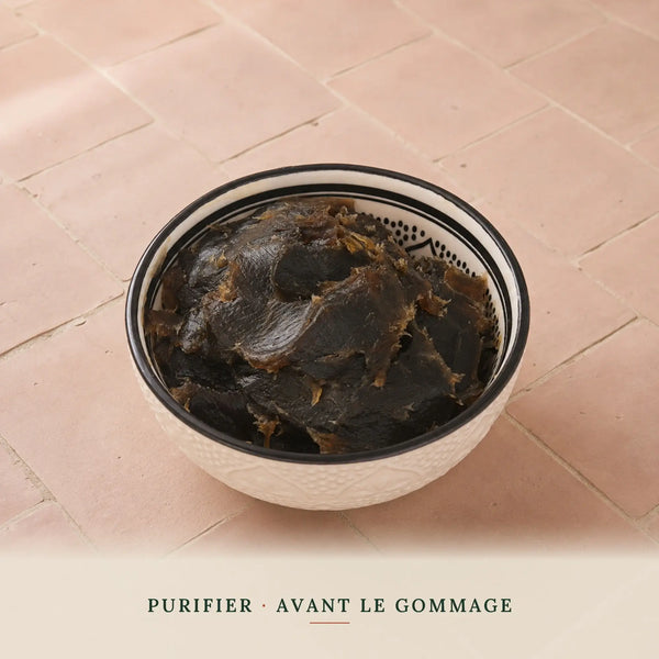Savon noir nature à la fleur d'oranger dans un bol marocain, texture brun-noir